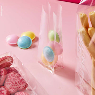 Sacchetto trasparenti a fondo quadro, ripieni di dolci e grissini, varie misure, su sfondo rosa